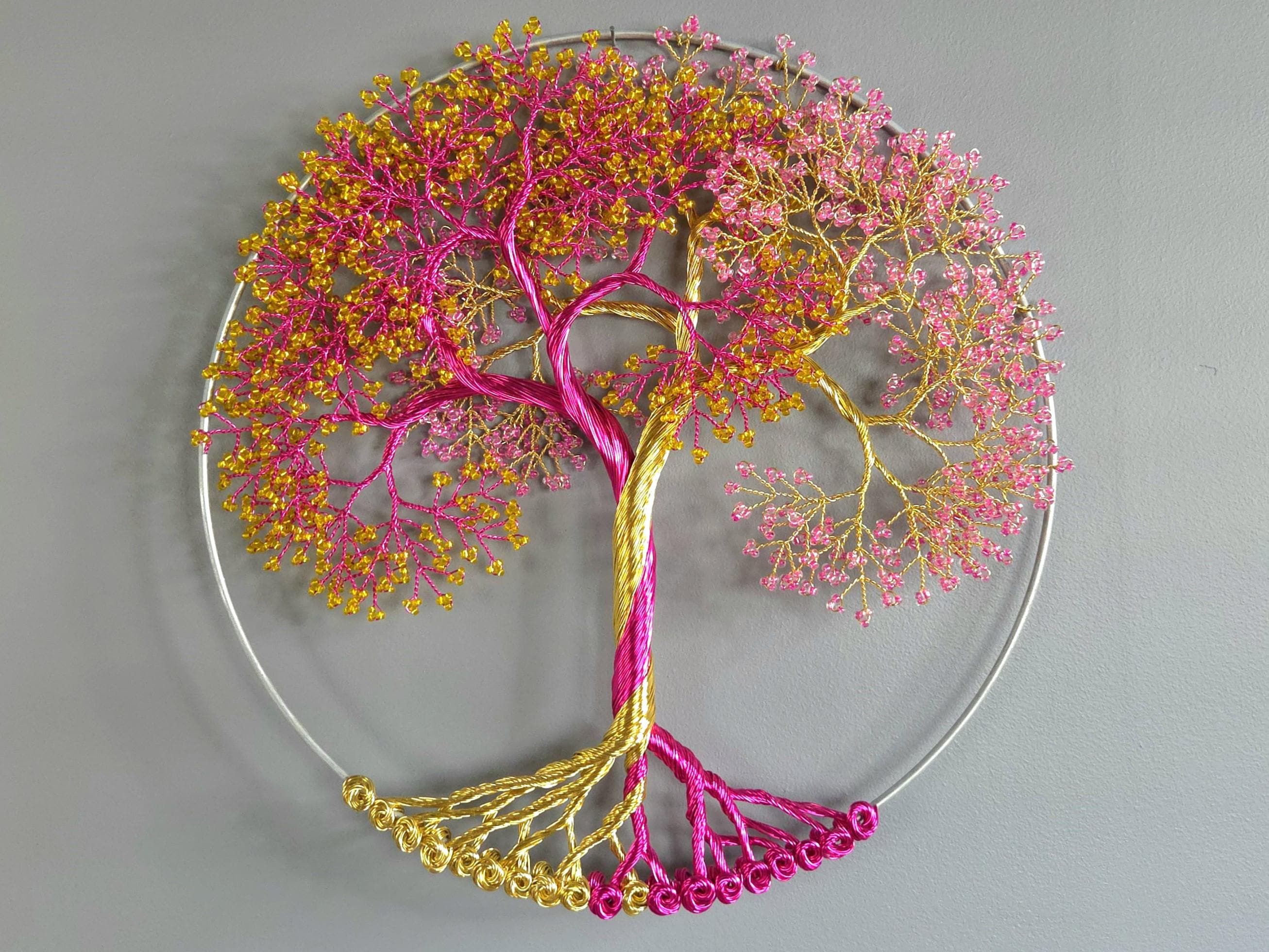 Decorative wall art of a tree with pink and gold branches on a gray background