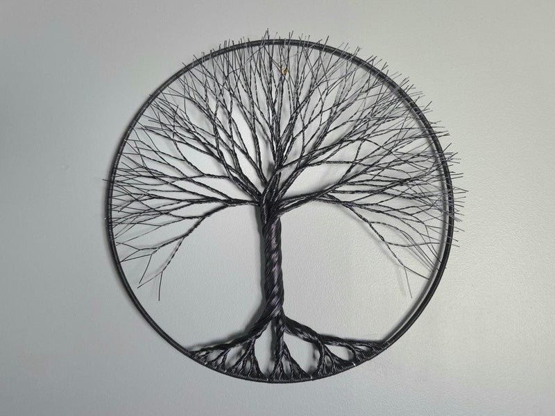 Decorative wall art of a tree with a peace symbol on a plain background