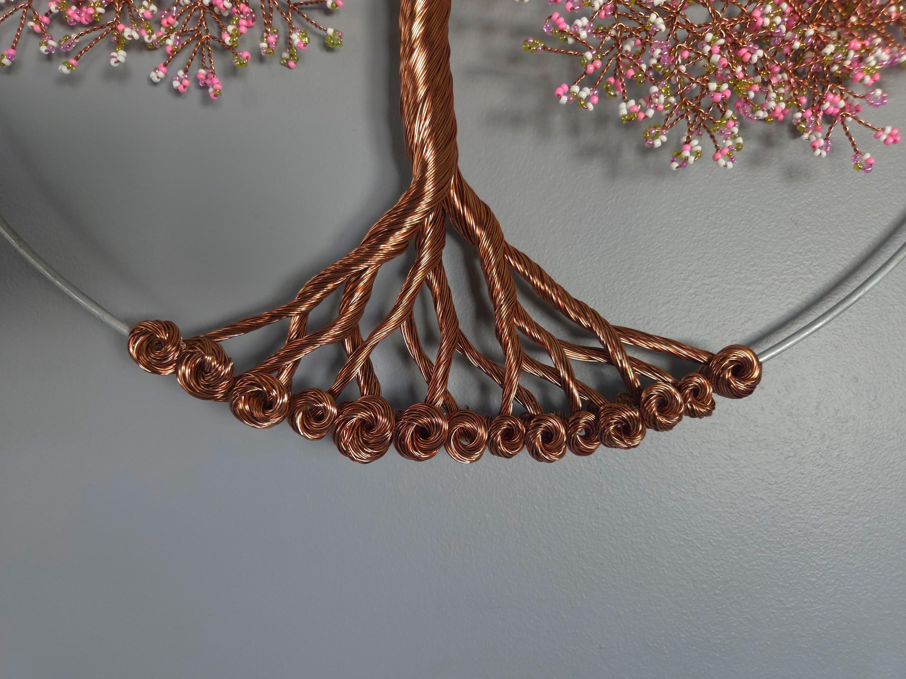 Decorative copper tree with pink flowers on a gray background