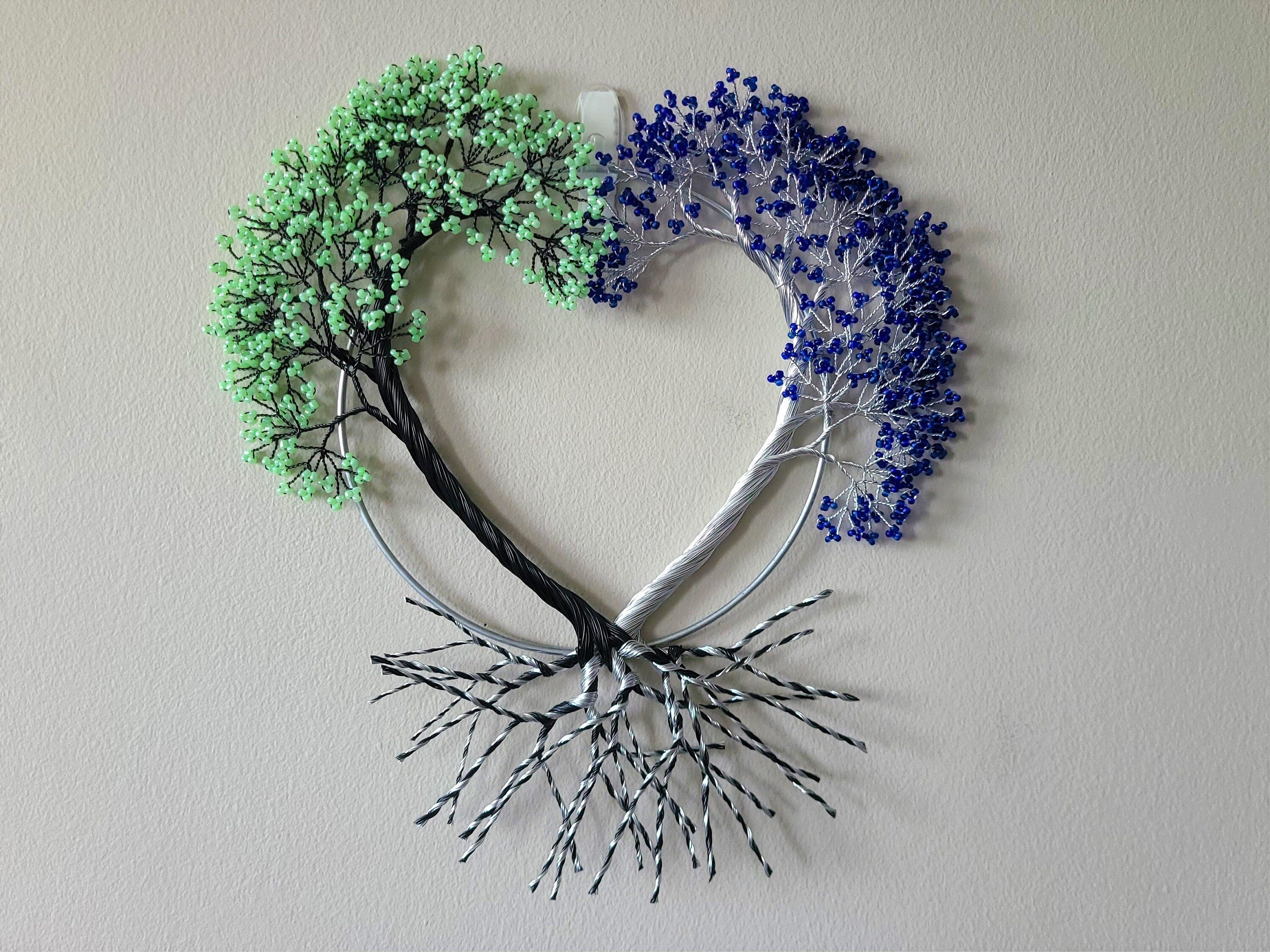 Heart-shaped decorative wall art with green and blue elements on a plain background