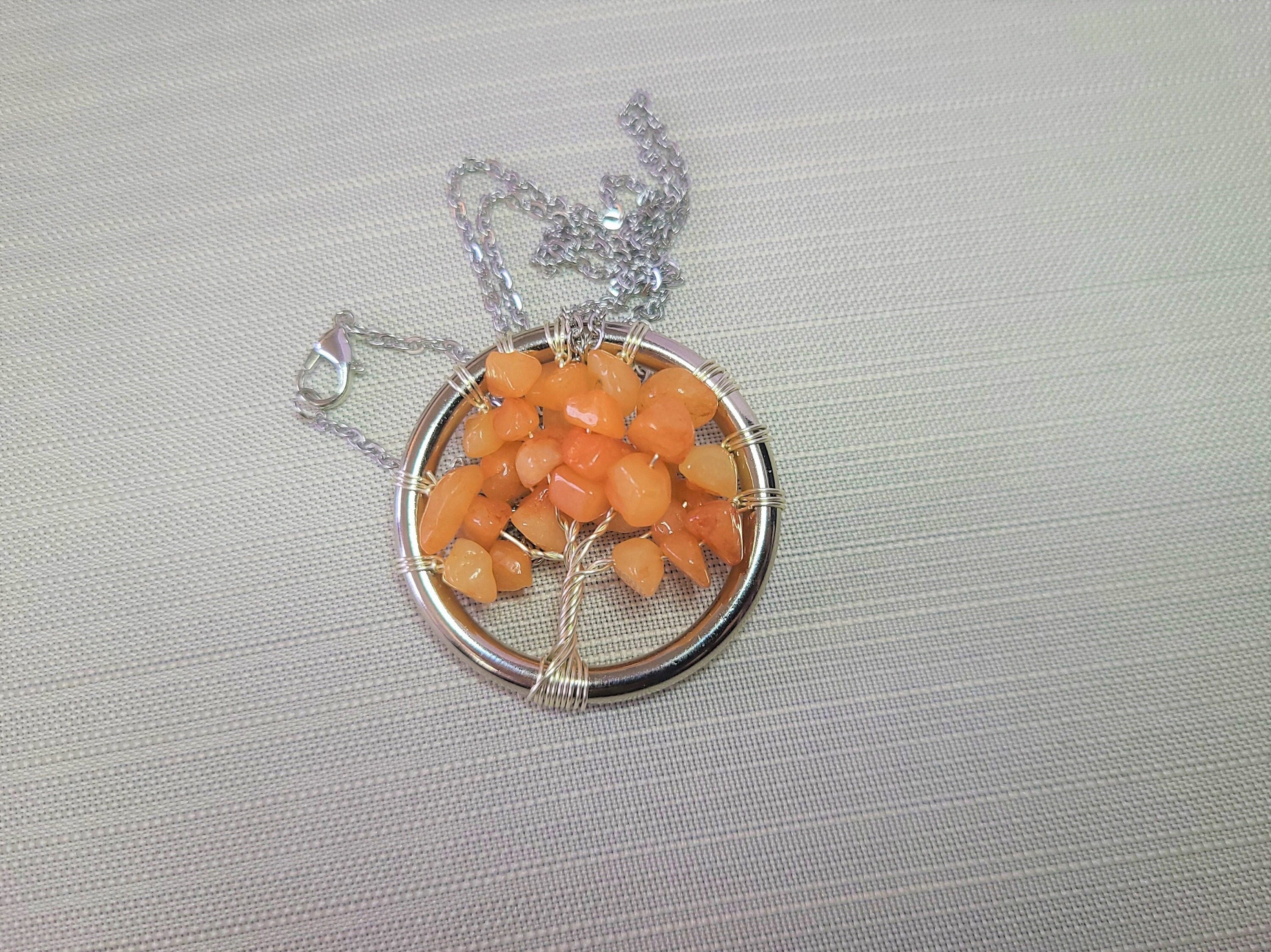 Necklace with a circular pendant featuring orange stones on a gray background