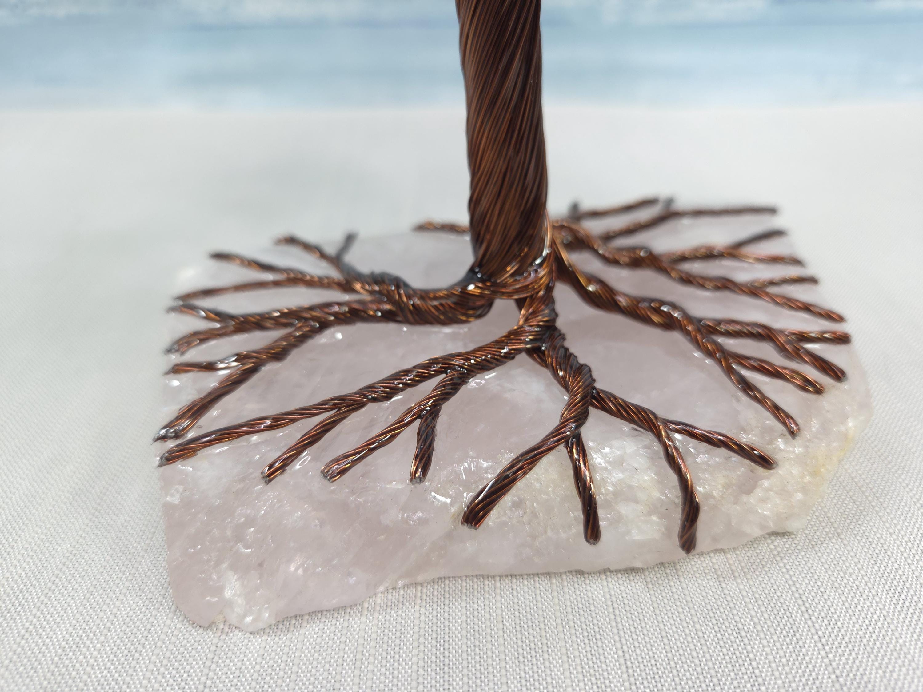 Decorative tree sculpture on a stone base with a light blue gradient background