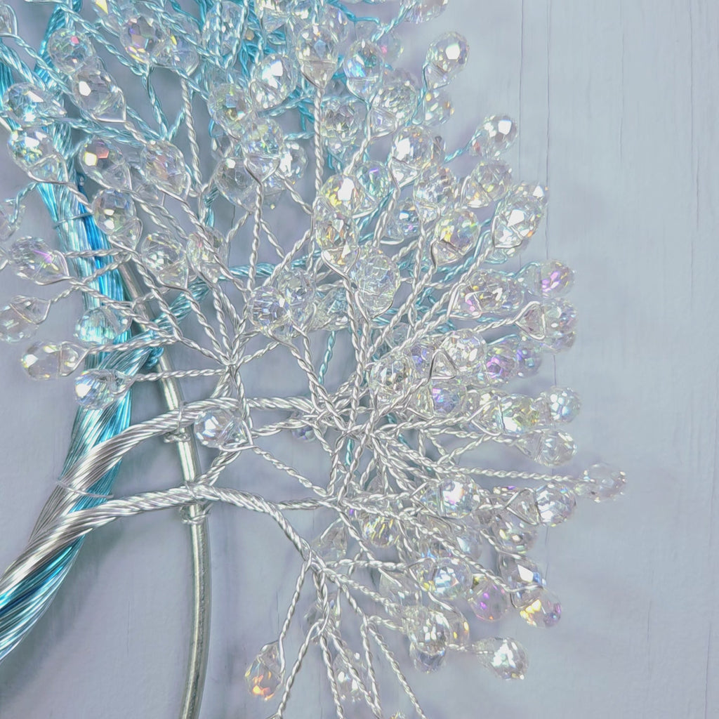 Decorative branch with blue and clear beads on a light wooden background