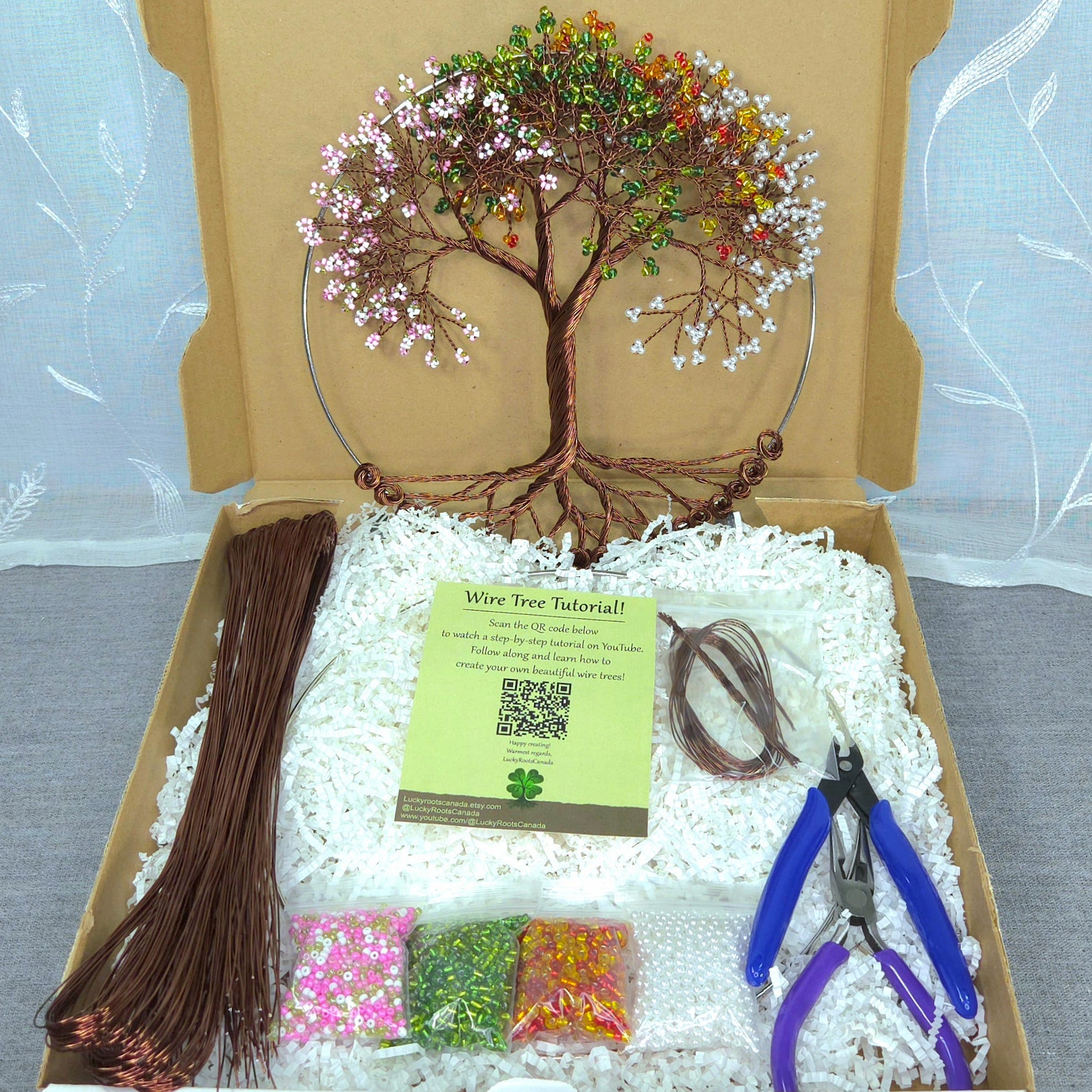 Craft kit with wire tree supplies including wires, tools, and a tree model in an open cardboard box.