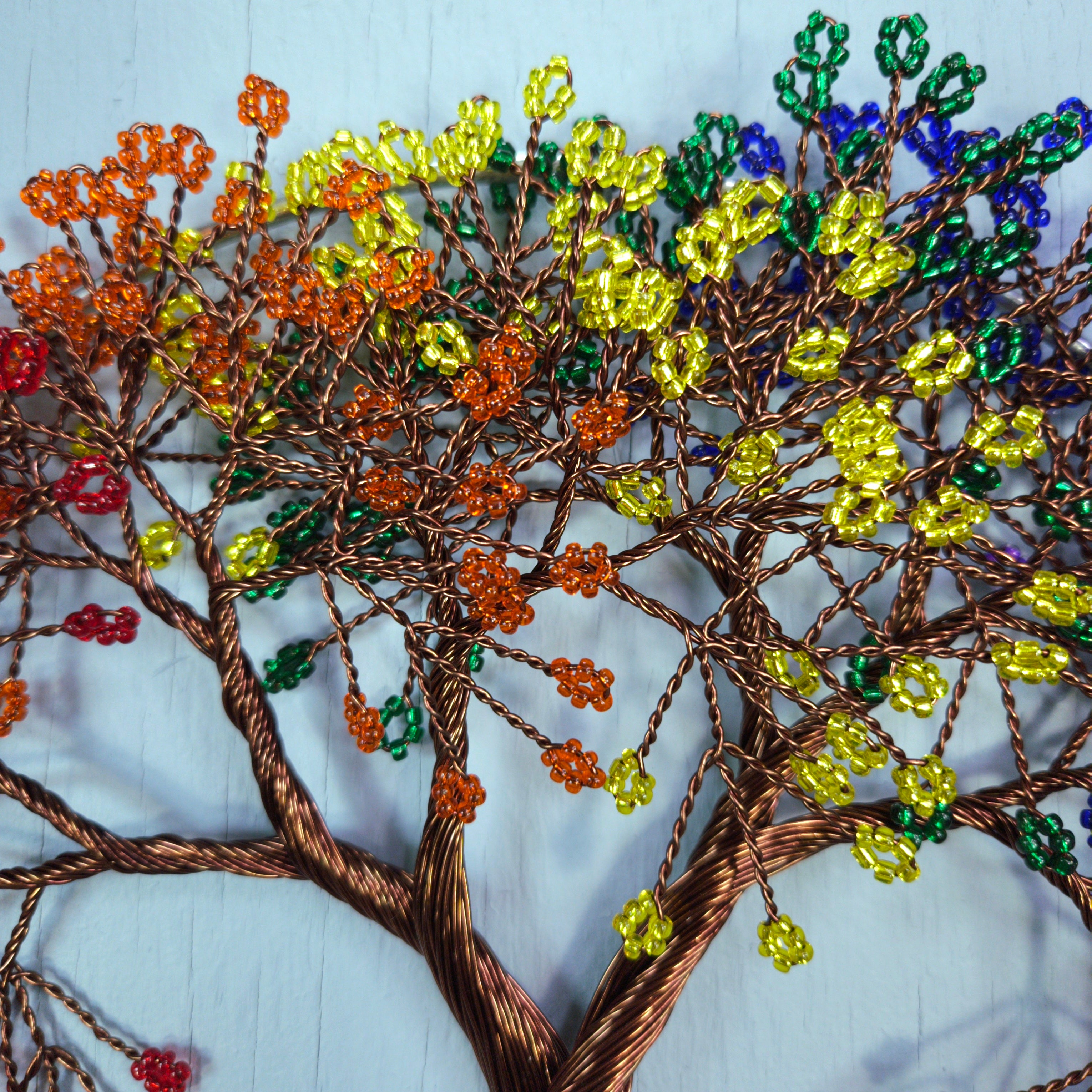 Colorful beaded tree sculpture on a textured white background